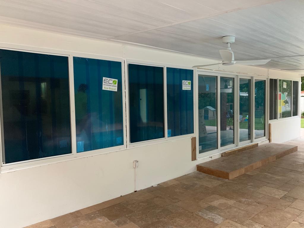 New impact windows with protective film installed on a covered patio