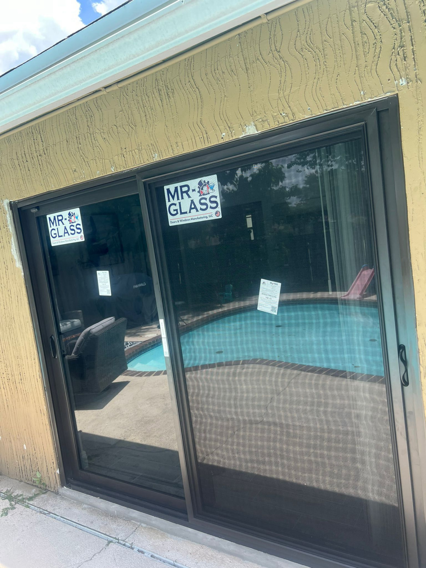 Bronze-framed impact sliding glass door installed on a pool patio