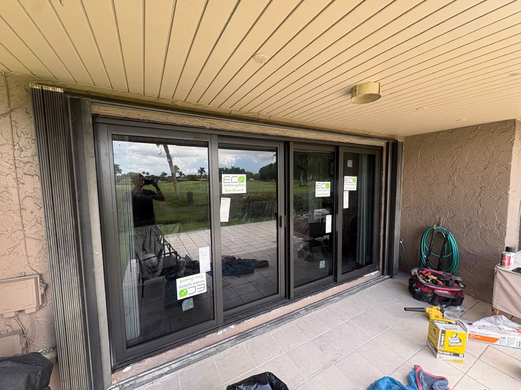 New four-panel impact sliding glass door installed on a golf course patio, tools being packed up