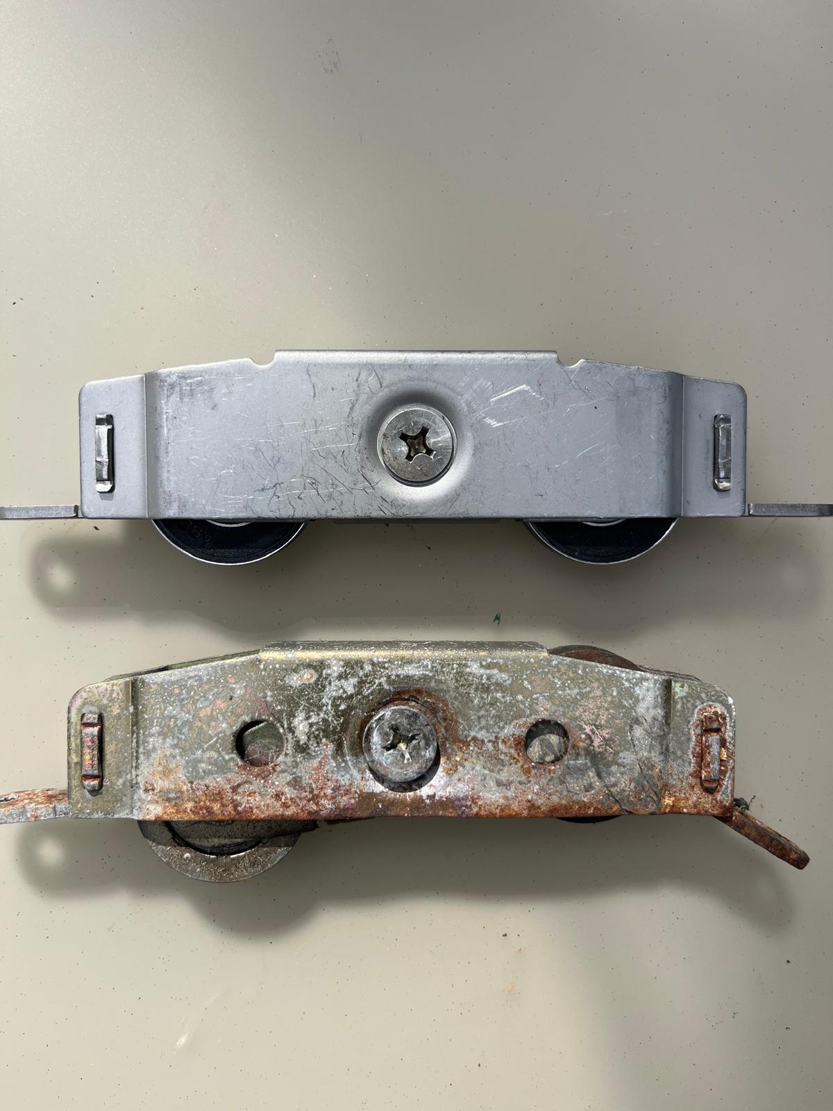 Worn sliding door roller next to a new heavy-duty stainless replacement roller