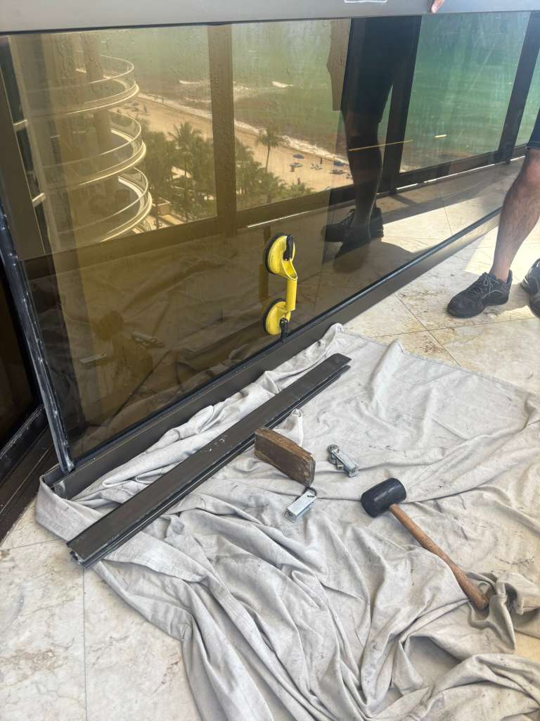 Sliding glass door panel being removed during a high-rise glass repair