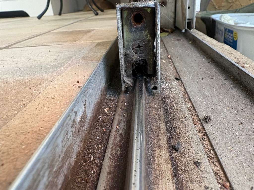 Worn sliding glass door track and roller bracket before repair