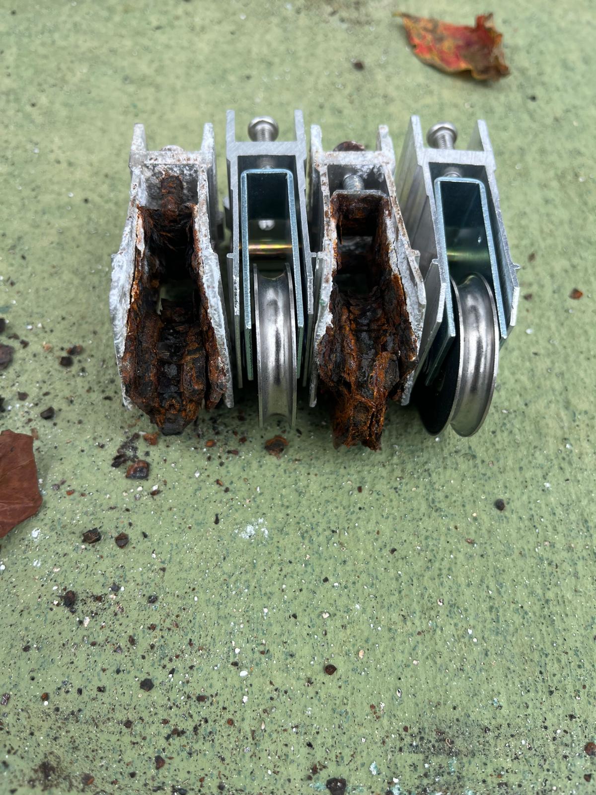 Salt-corroded sliding glass door roller assemblies pulled from a patio door