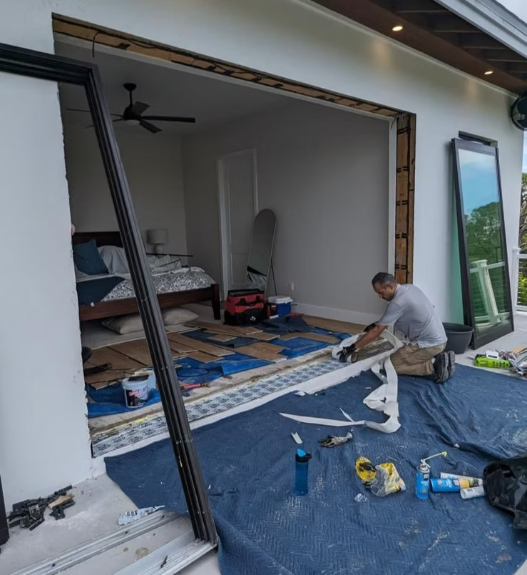 Technician replacing a large impact sliding glass door system in a master bedroom opening