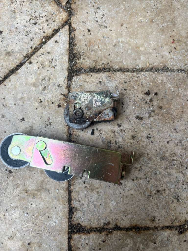 Rusted sliding door roller next to a new replacement roller assembly