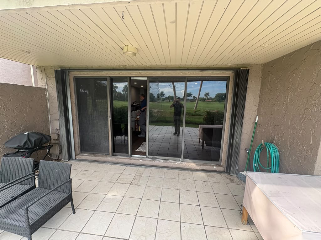 Old white-framed sliding glass door before replacement on a golf course home